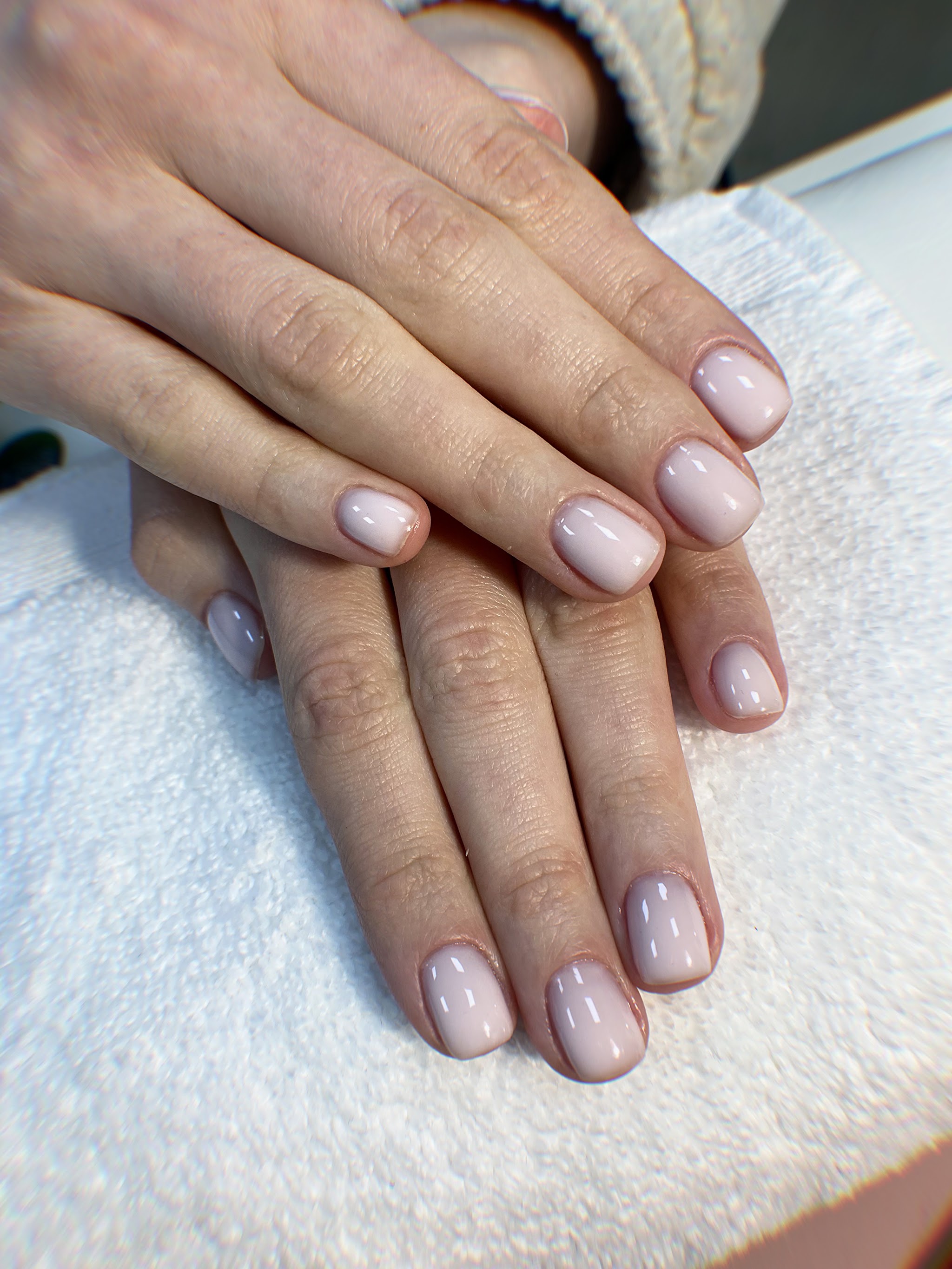 Zachte nude gelmanicure op een witte handdoek