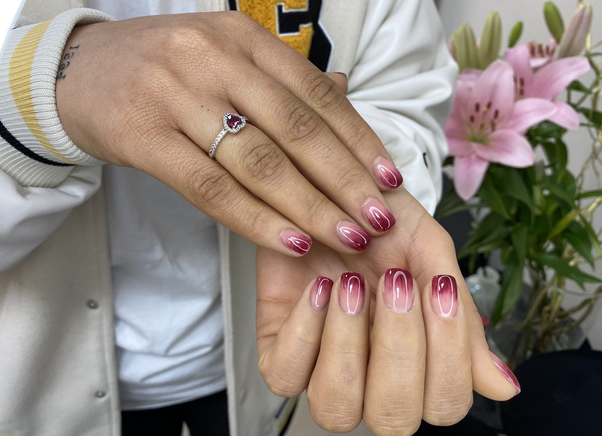 Bordeaux ombre nagels met lelies op de achtergrond