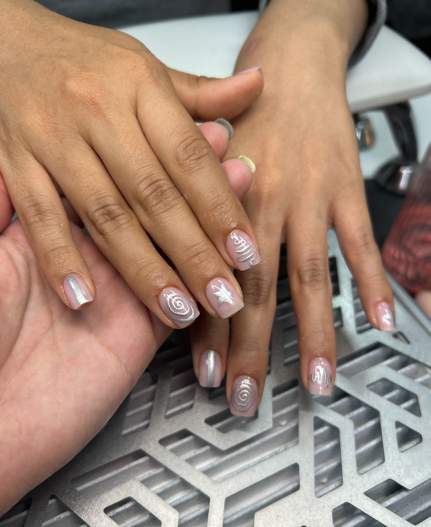 Zilveren parelmoer nagels met witte krullen, twee paar handen op de stofafzuiging
