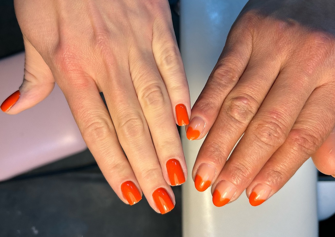 Oranje nagels, twee handen op een lamp